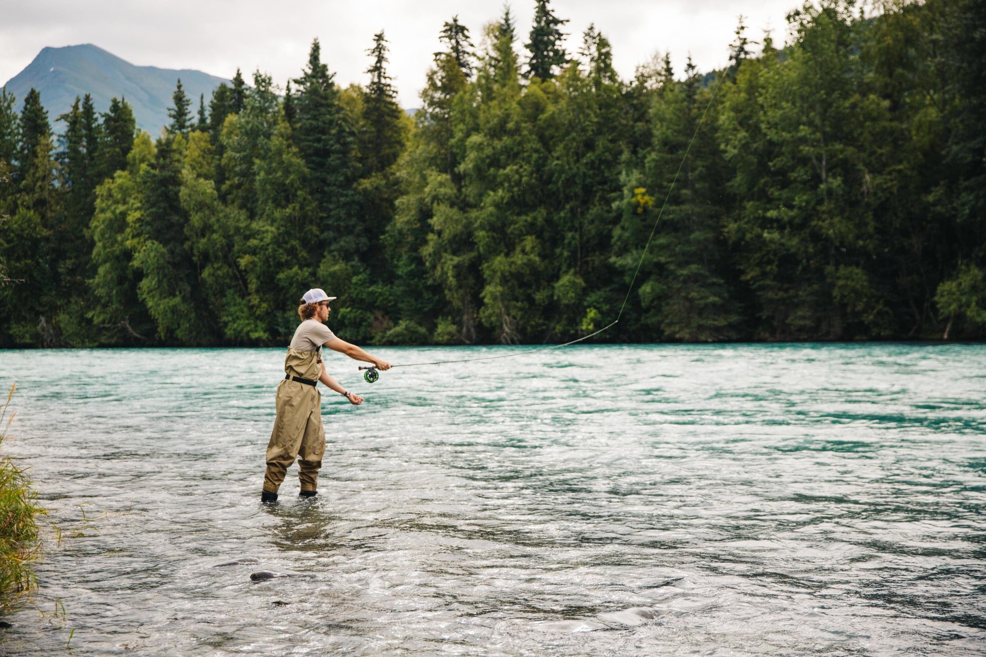 Fly fisherman casting on a turquoise Alaskan river