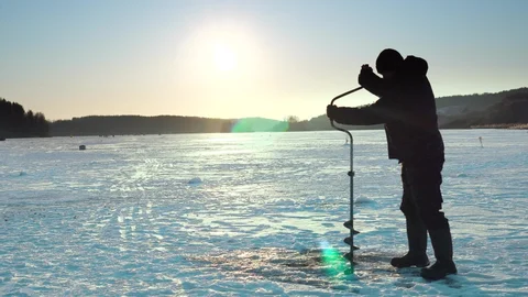 Angler winter fishing by snowy river